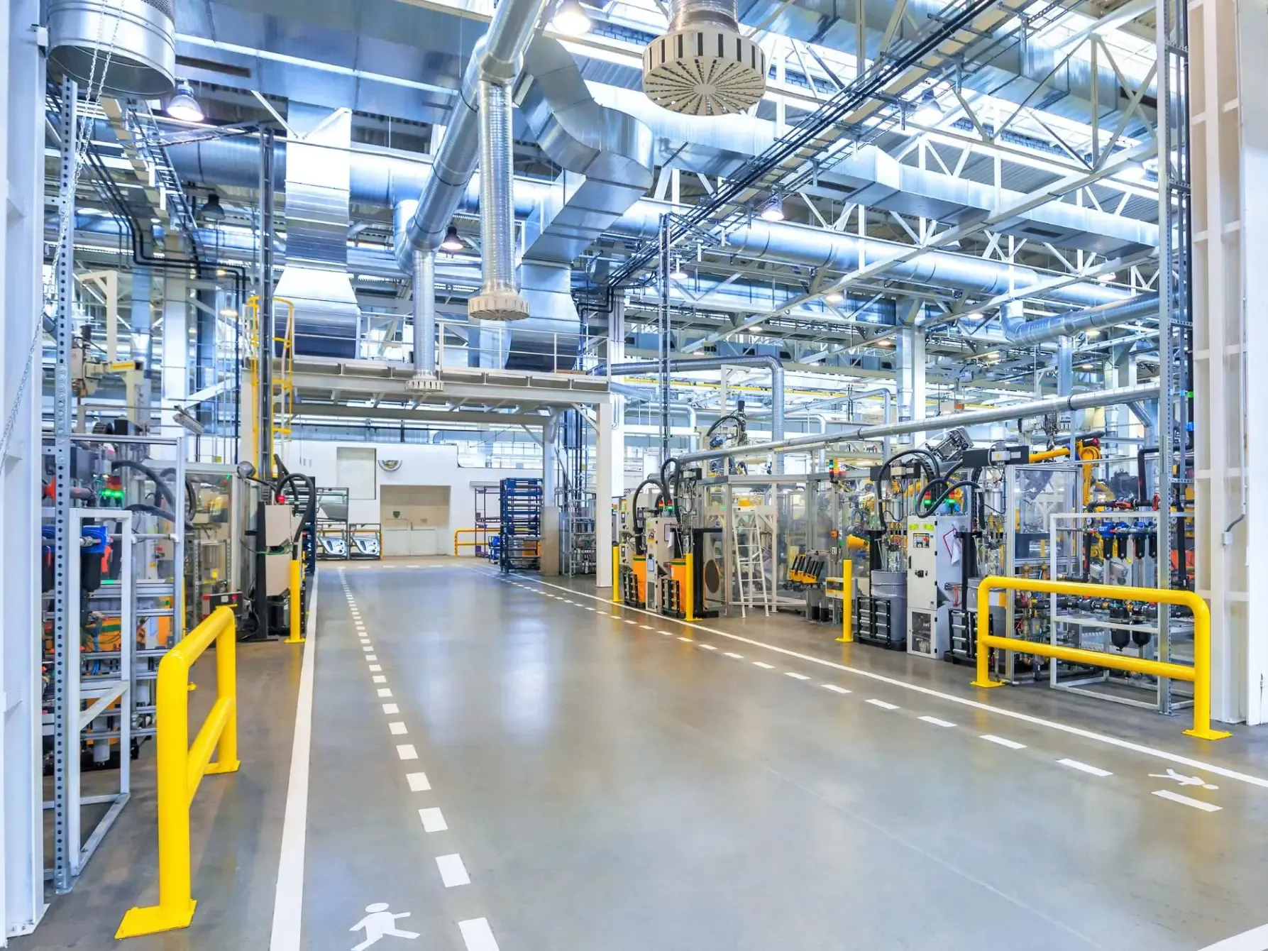 Industrihall med maskinlinjer, kabelstegar och ventilationstrummor i taket.